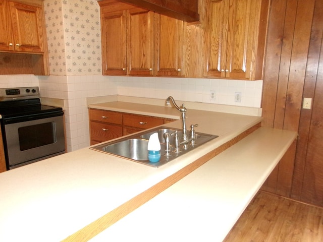 934 Sunset Blvd, Elba, AL 36323 - kitchen with stainless steel electric range, brown cabinets, light countertops, light wood-type flooring, and wallpapered walls