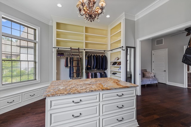 spacious closet with visible vents, ceiling fan with notable chandelier, and dark wood-type flooring