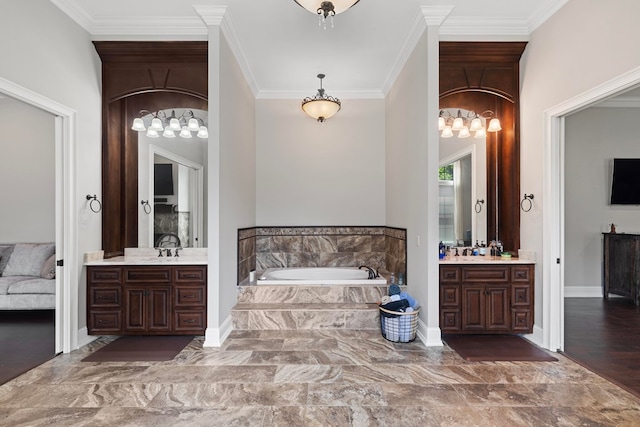 full bath featuring ornamental molding, baseboards, a garden tub, and two vanities