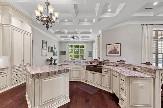 kitchen with beam ceiling, a large island, a sink, coffered ceiling, and dark wood finished floors