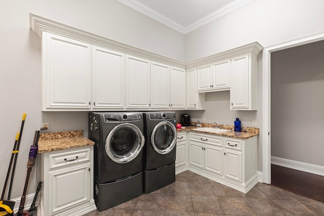 washroom featuring baseboards, ornamental molding, separate washer and dryer, cabinet space, and a sink