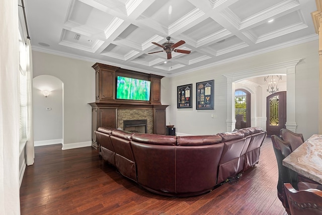 living area with arched walkways, a ceiling fan, dark wood-style flooring, and a fireplace