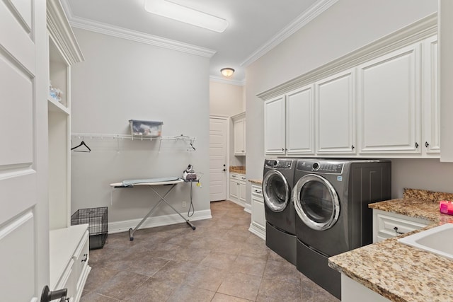 laundry room with a sink, crown molding, cabinet space, and washing machine and clothes dryer