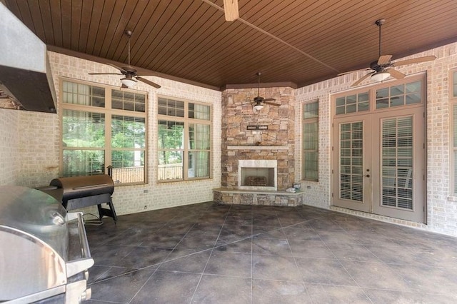 view of patio with area for grilling, french doors, an outdoor stone fireplace, and ceiling fan