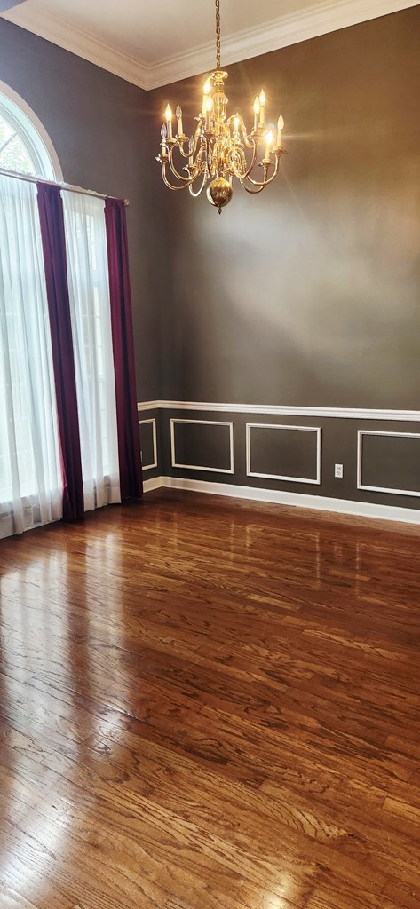 301 Roslyn Glen Way, Dothan, AL 36305 - spare room featuring a chandelier, wood finished floors, plenty of natural light, crown molding, and a decorative wall