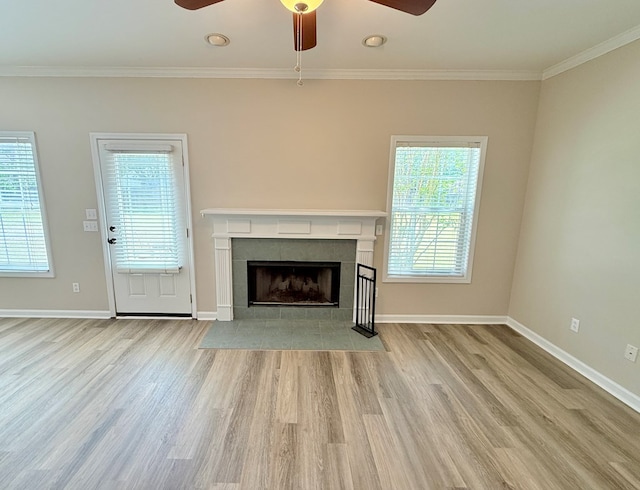 unfurnished living room featuring a tiled fireplace, wood finished floors, a ceiling fan, and ornamental molding