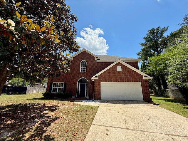 traditional-style house featuring a garage, fence, concrete driveway, a front yard, and brick siding