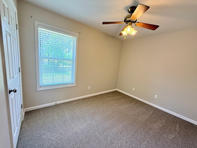 spare room featuring baseboards, a ceiling fan, and dark carpet