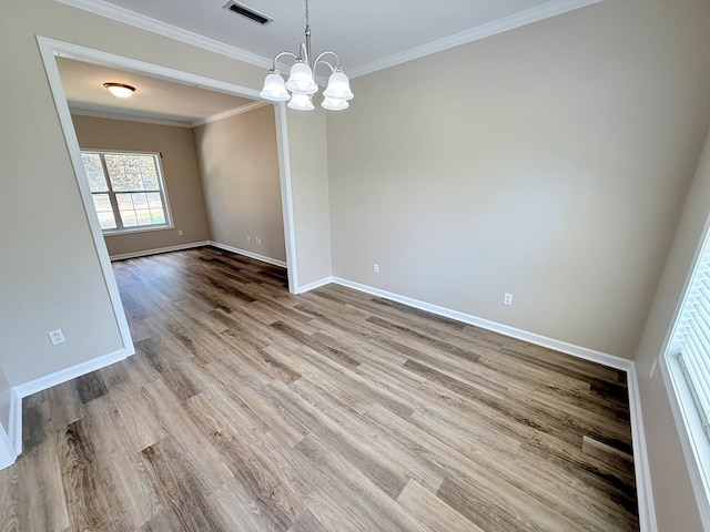 spare room with baseboards, visible vents, a chandelier, crown molding, and wood finished floors