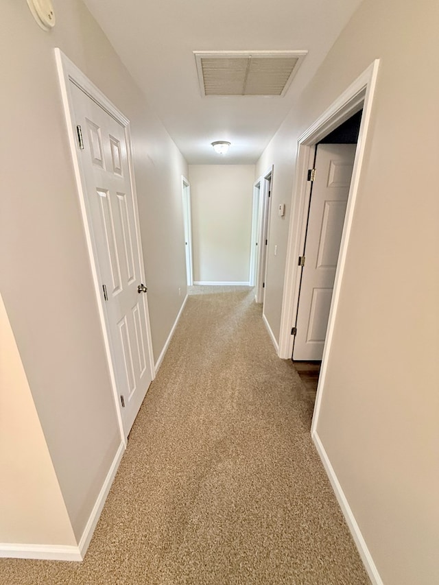 hallway with carpet, baseboards, and visible vents