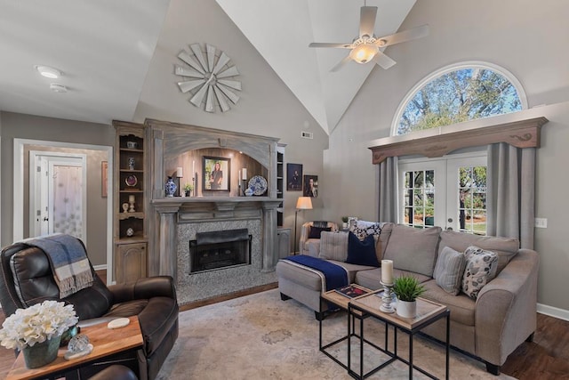 living room with ceiling fan, french doors, high vaulted ceiling, and light wood-type flooring