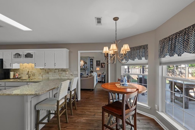 kitchen featuring dark hardwood / wood-style floors, white cabinetry, hanging light fixtures, and a wealth of natural light