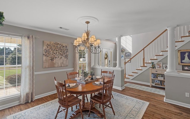 dining space with ornate columns, a chandelier, wood-type flooring, and ornamental molding