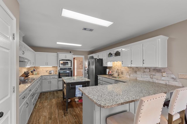 kitchen featuring stainless steel appliances, sink, white cabinets, dark hardwood / wood-style floors, and a kitchen island