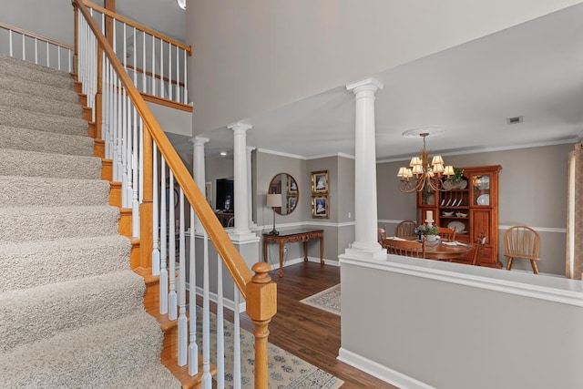 stairs featuring hardwood / wood-style floors, an inviting chandelier, and ornamental molding