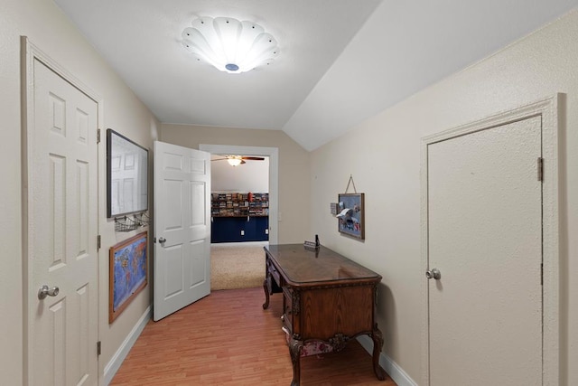 hallway featuring light wood-type flooring and vaulted ceiling