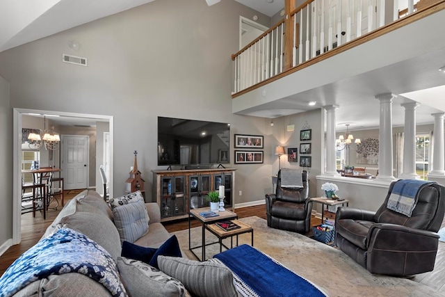 living room with a chandelier, hardwood / wood-style floors, decorative columns, and high vaulted ceiling