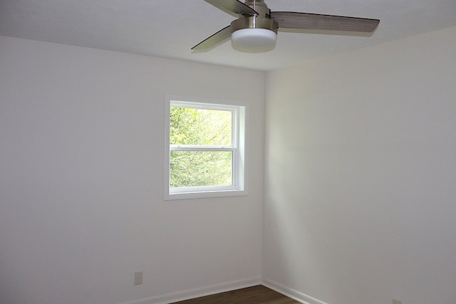 empty room featuring a ceiling fan, dark wood-type flooring, and baseboards