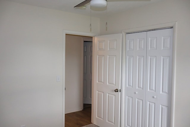 unfurnished bedroom with dark wood-style floors, a closet, baseboards, and ceiling fan
