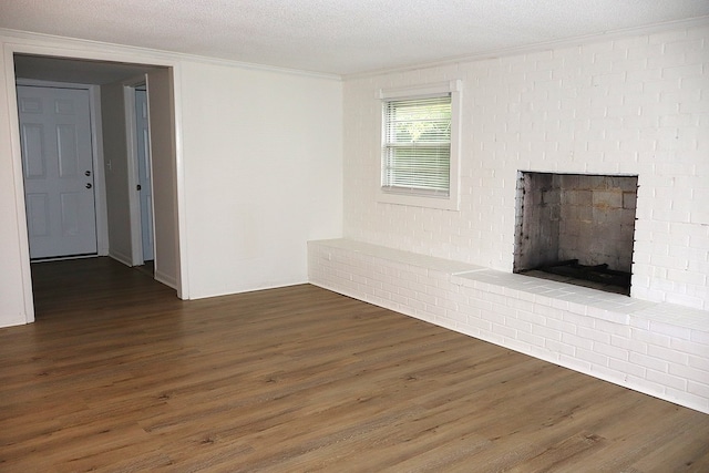 unfurnished living room featuring dark wood-style floors, a fireplace, ornamental molding, and a textured ceiling