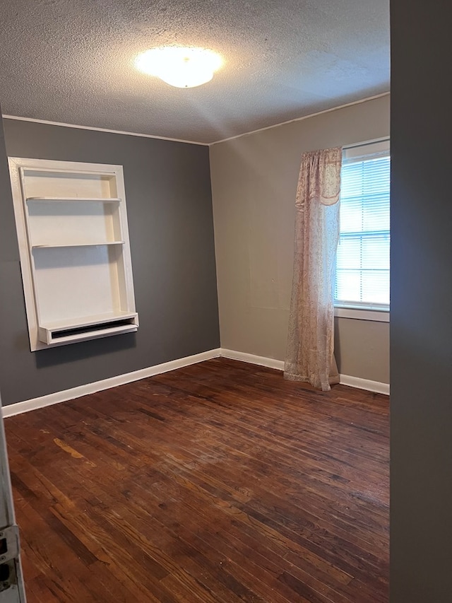 spare room featuring a textured ceiling, dark hardwood / wood-style floors, and crown molding