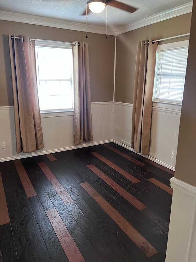 empty room featuring a textured ceiling, ceiling fan, dark hardwood / wood-style flooring, and crown molding