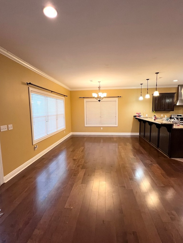 unfurnished living room featuring crown molding, dark hardwood / wood-style flooring, and a notable chandelier