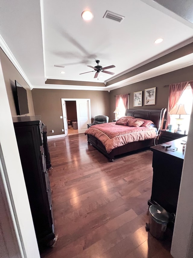 bedroom featuring dark hardwood / wood-style flooring, a raised ceiling, ceiling fan, and ornamental molding