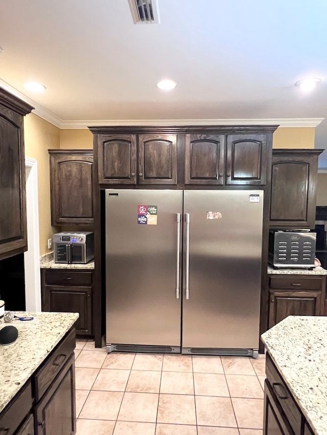 kitchen featuring dark brown cabinetry, stainless steel refrigerator, and crown molding