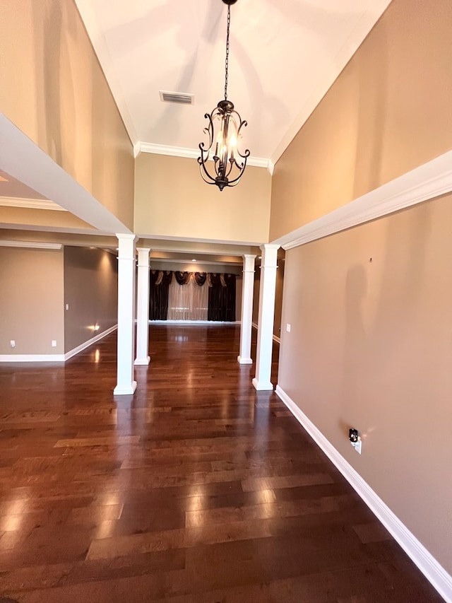 foyer entrance featuring dark wood-type flooring, a towering ceiling, a chandelier, a tiled fireplace, and ornamental molding