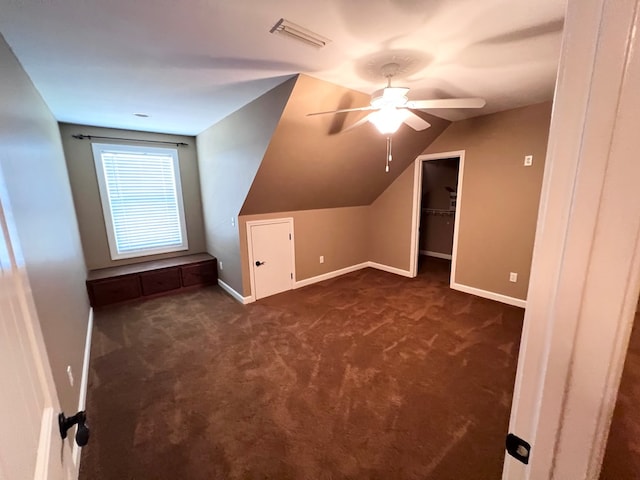 additional living space with dark colored carpet, ceiling fan, and lofted ceiling