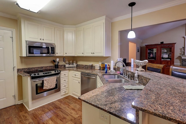 kitchen featuring appliances with stainless steel finishes, a sink, a peninsula, light wood-style floors, and ornamental molding
