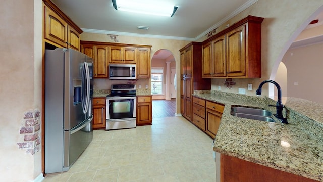 kitchen with sink, light stone countertops, stainless steel appliances, and ornamental molding