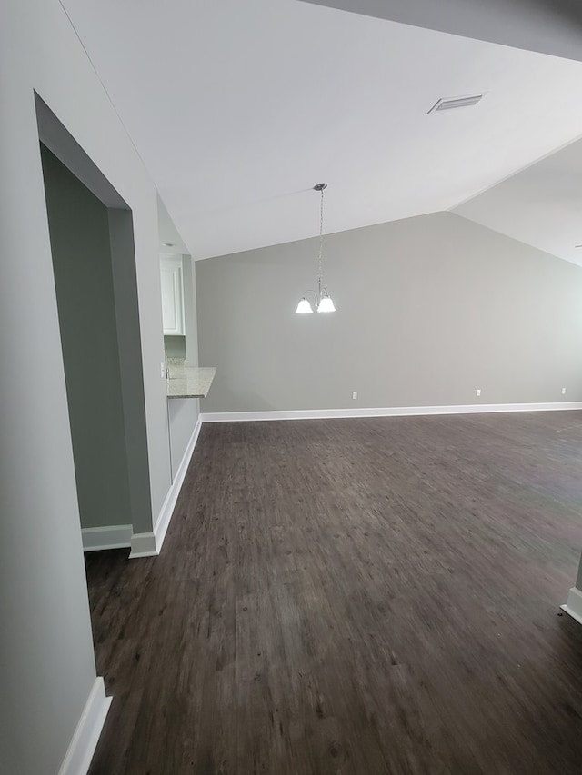 unfurnished living room featuring a chandelier, dark wood-type flooring, and vaulted ceiling