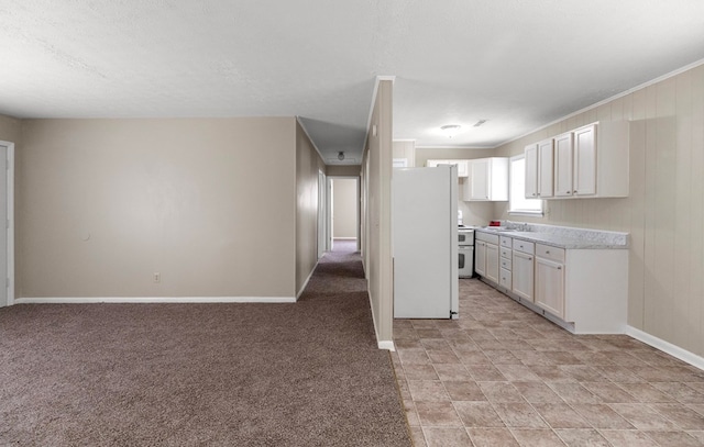 kitchen with sink, white cabinets, white fridge, light colored carpet, and a textured ceiling