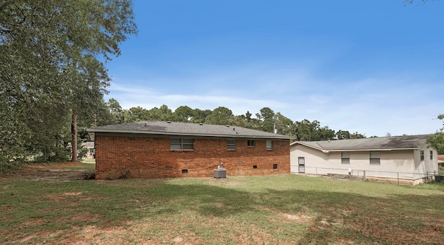 back of house featuring central AC unit and a lawn