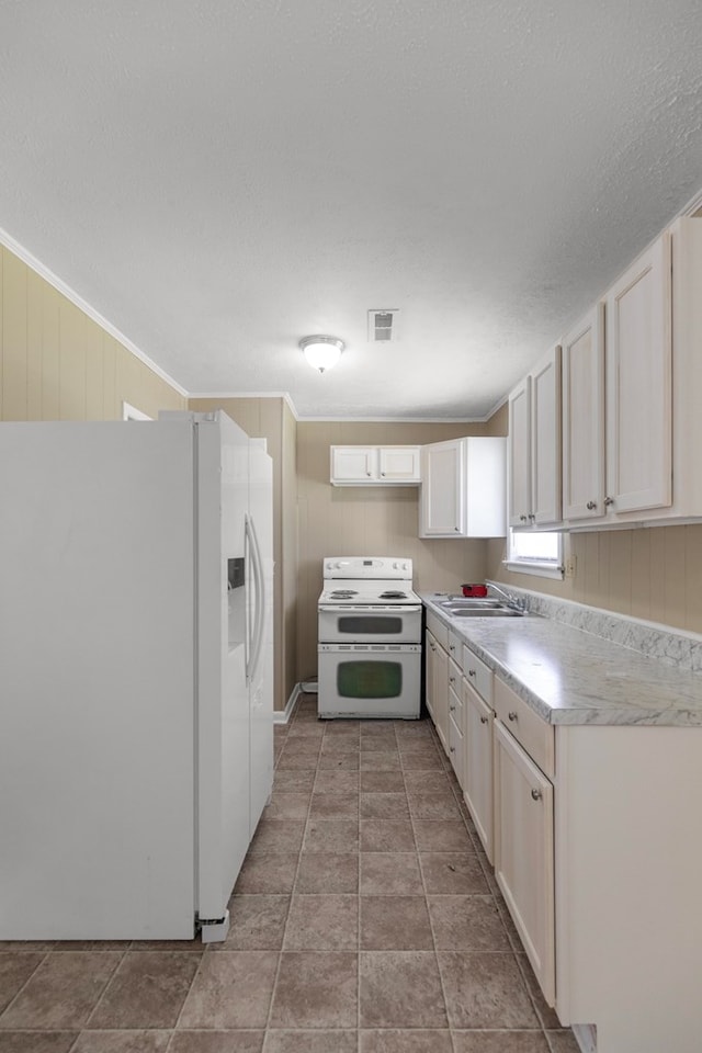 kitchen featuring sink, crown molding, white appliances, wooden walls, and white cabinets