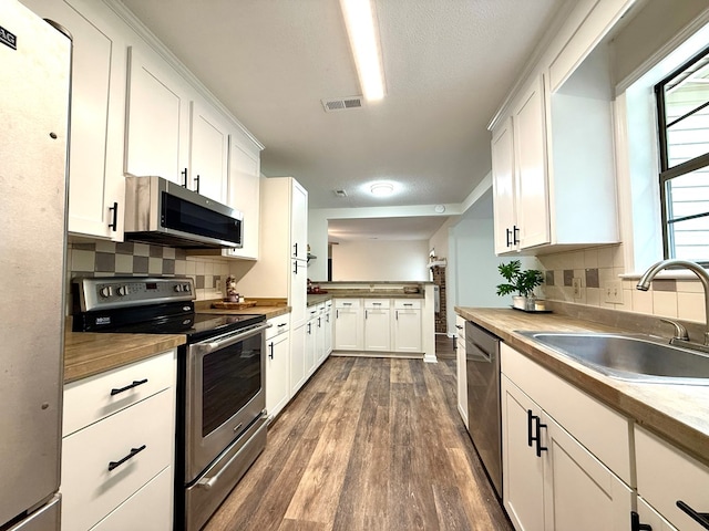 2419 Creekwood Dr, Dothan, AL 36301 - kitchen with stainless steel appliances, backsplash, dark wood-type flooring, and white cabinetry