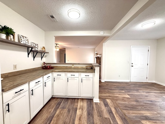 2419 Creekwood Dr, Dothan, AL 36301 - kitchen featuring open shelves, a textured ceiling, a peninsula, dark wood-style floors, and white cabinetry