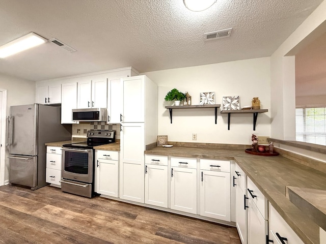 2419 Creekwood Dr, Dothan, AL 36301 - kitchen with stainless steel appliances, open shelves, white cabinetry, dark wood-style flooring, and a textured ceiling