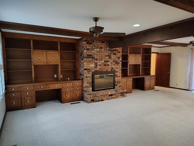 unfurnished living room with beam ceiling, a brick fireplace, built in features, light carpet, and built in desk