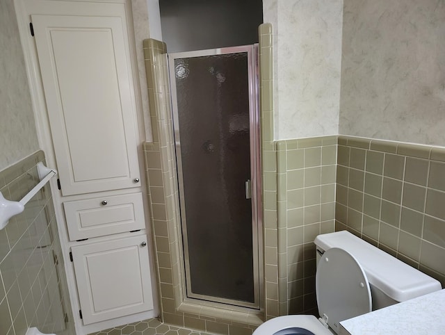 bathroom featuring toilet, a shower with door, and tile walls