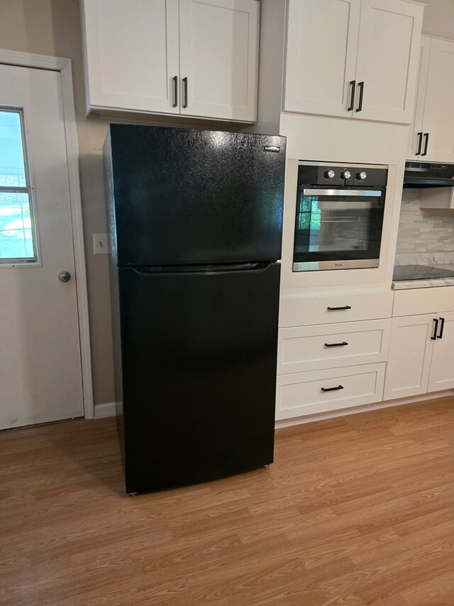 100 Pridmore St, Daleville, AL 36322 - kitchen featuring black appliances, light wood-type flooring, white cabinets, under cabinet range hood, and tasteful backsplash