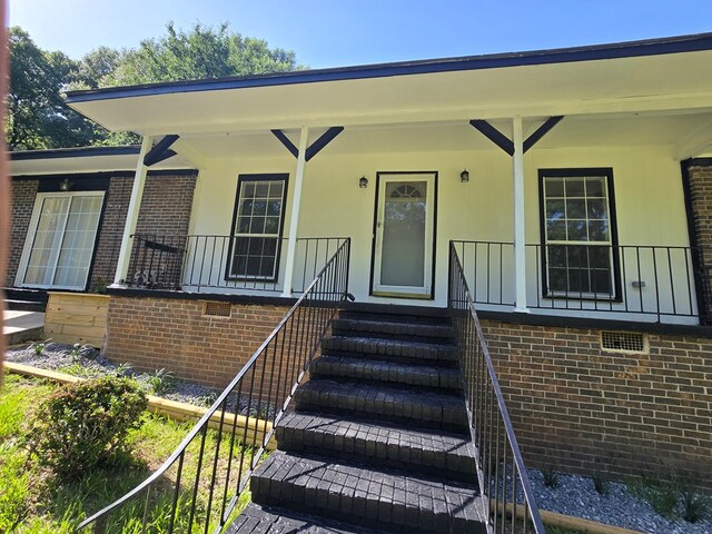 100 Pridmore St, Daleville, AL 36322 - doorway to property featuring a porch, crawl space, and brick siding