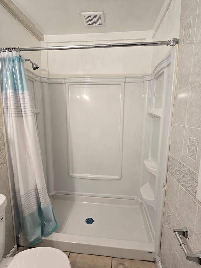 100 Pridmore St, Daleville, AL 36322 - full bathroom featuring a shower stall, toilet, tile patterned flooring, and tile walls