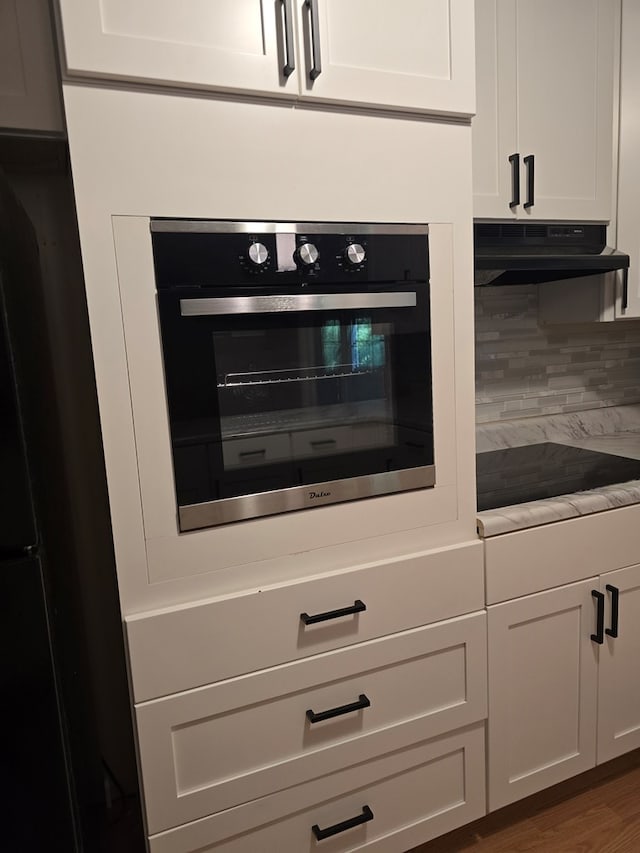 100 Pridmore St, Daleville, AL 36322 - kitchen view of black appliances, extractor fan, white cabinetry, backsplash, and light countertops
