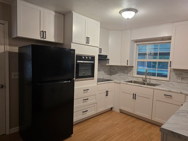100 Pridmore St, Daleville, AL 36322 - kitchen featuring black appliances, a sink, tasteful backsplash, light wood-style flooring, and white cabinets