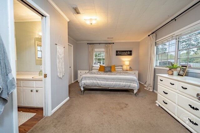 bedroom with ensuite bathroom, carpet floors, ornamental molding, and multiple windows