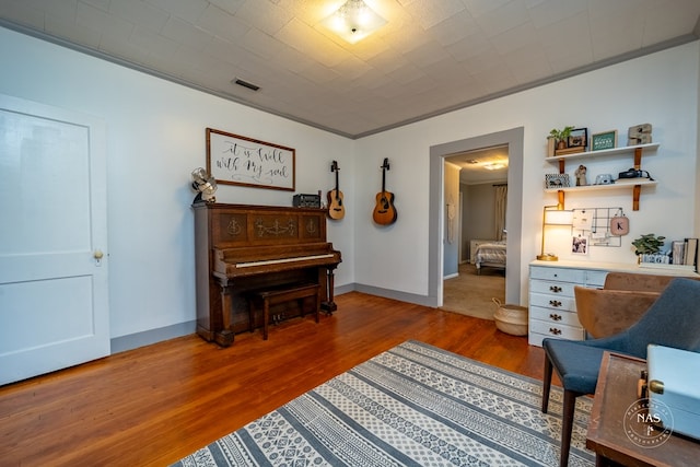 living area with hardwood / wood-style flooring and crown molding