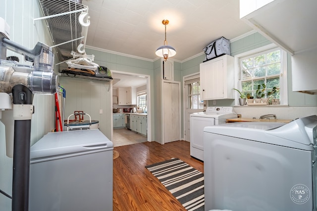 washroom featuring hardwood / wood-style floors, washer and dryer, cabinets, and ornamental molding